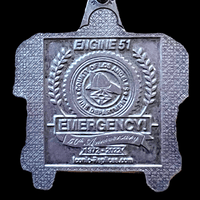 Metal badge with 'Engine 51' and 'Emergency!' text on a black background