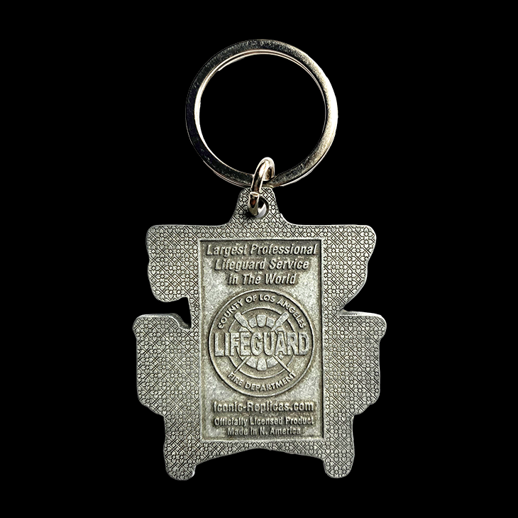 Metal keychain shaped like a life preserver with 'Largest Professional Lifeguard Service in the World County of Los Angeles Fire Department LIFEGUARD'  Lifeguard logo, then IconicReplicas.com Officially licensed product Made in N. Americaltext on a gray metal background